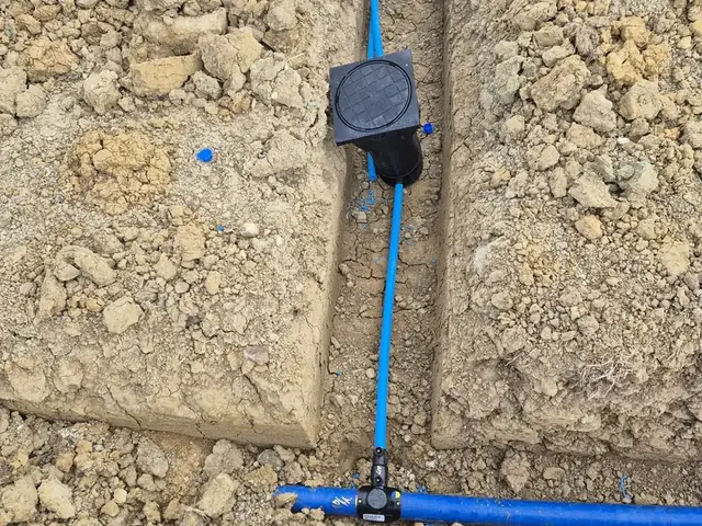 New blue MDPE supply pipe run to a boundary box in a narrow trench