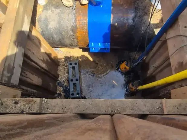 Blue gate valve fitted to a large water main in a timber-shored excavation