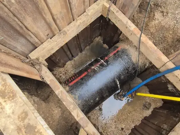 Large water main exposed in a timber-shored pit ready for a connection