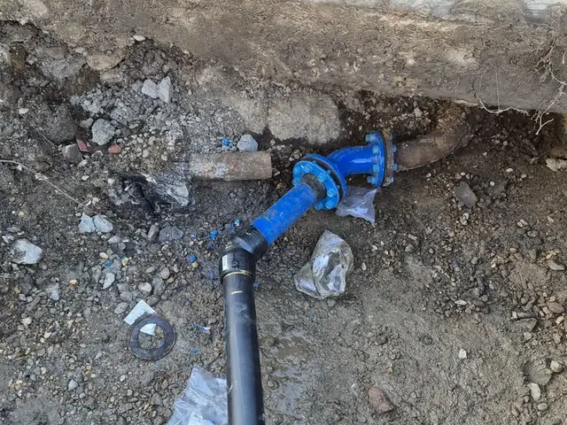 Gate valve and pipework exposed in an excavation at a road edge