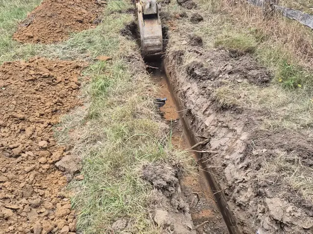 Excavating a narrow service trench across a field