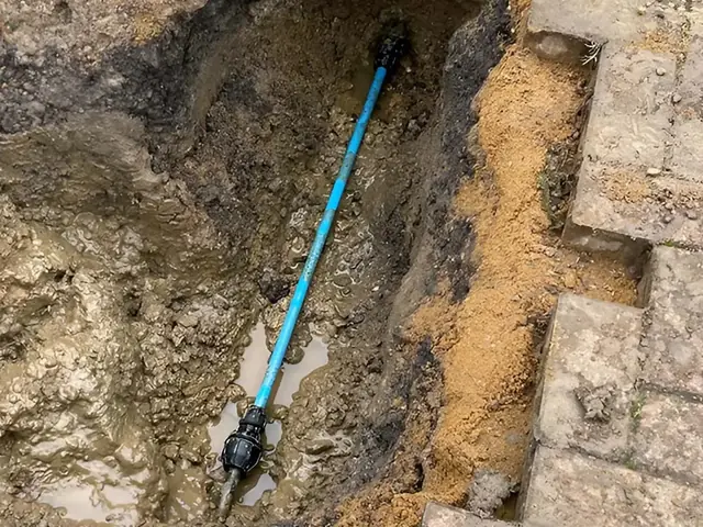 New MDPE supply pipe connected up in a small excavation beside a wall