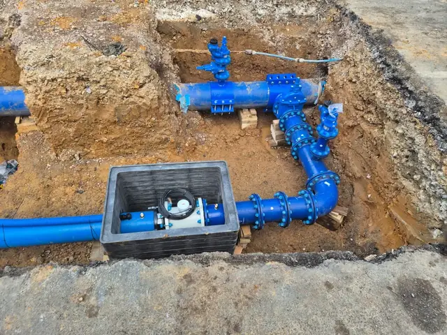 New water connection — blue valve assembly and meter chamber set in the ground