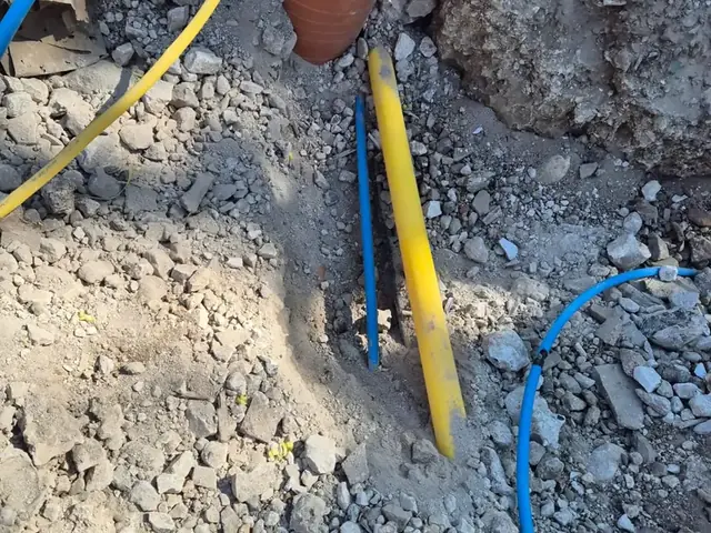Yellow gas and blue water services alongside a clay drainage pipe