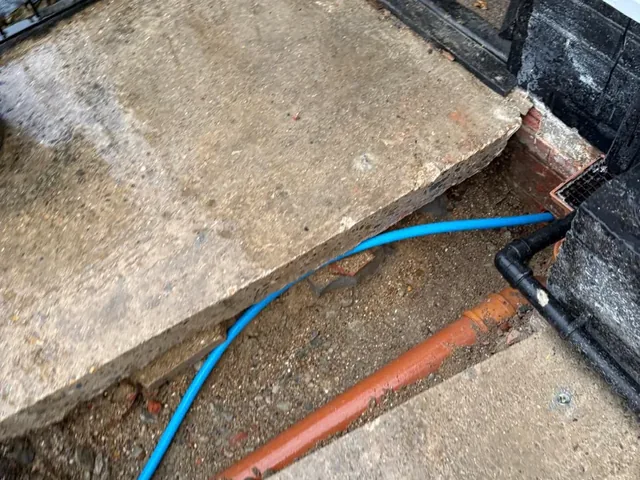 New blue MDPE supply pipe run under the entrance step and connected