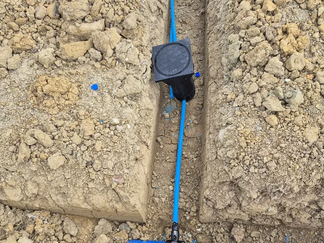 Boundary box and service tee on a new blue MDPE water main in a narrow trench