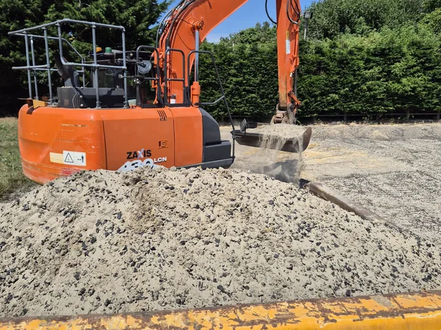 Excavator loading arisings into a skip beside a compacted oversite sub-base