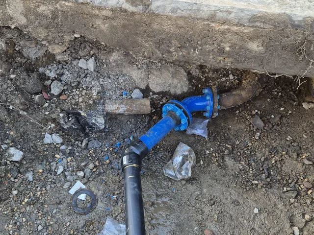 Flanged blue valve connecting new pipework to an existing cast-iron main