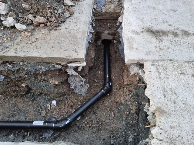 New black drainage run laid to an inspection chamber beneath a concrete path