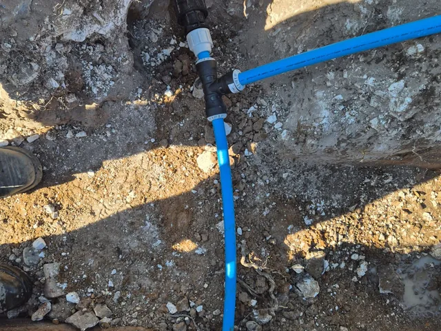 New blue MDPE tee and compression fittings on a repaired supply