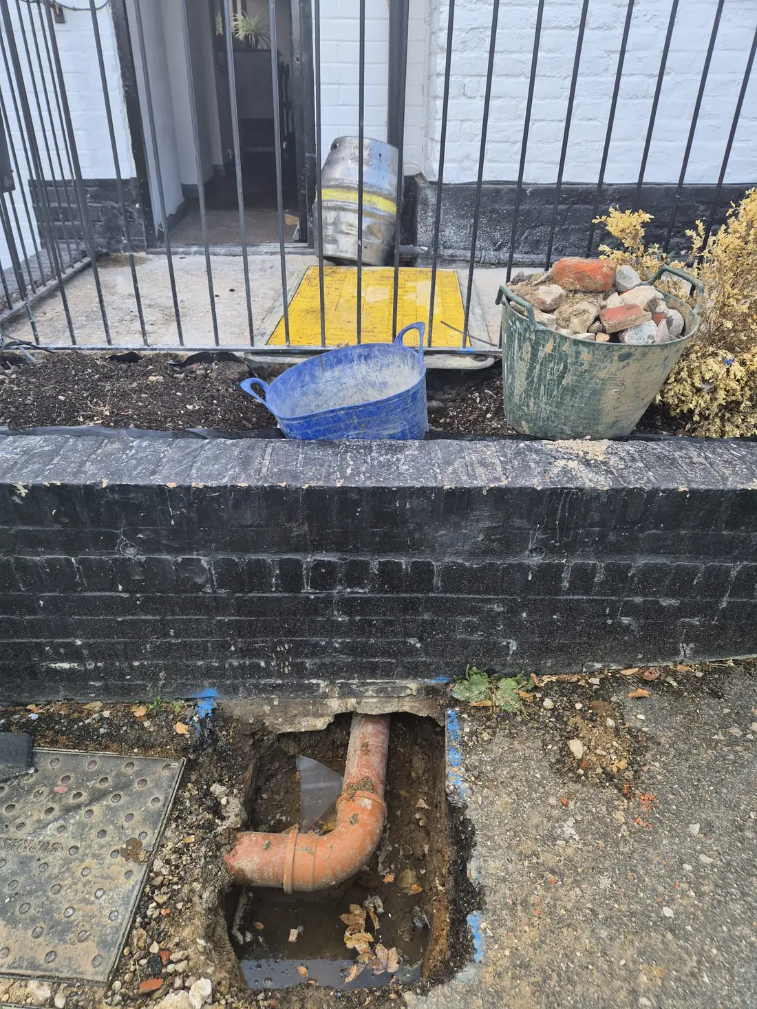 The excavation at the base of the pub wall with the old pipework exposed The excavation at the base of the pub wall with the old pipework exposed