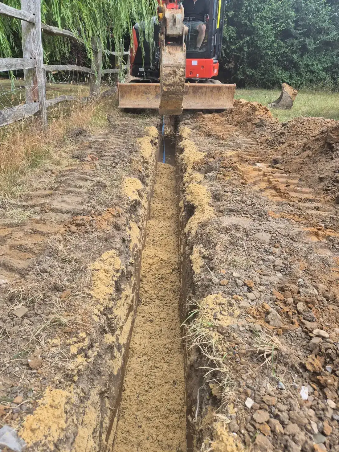 The new supply pipe bedded and covered with sand along the trench The new supply pipe bedded and covered with sand along the trench